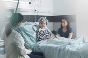 A child wearing an EEG cap sits on a hospital bed