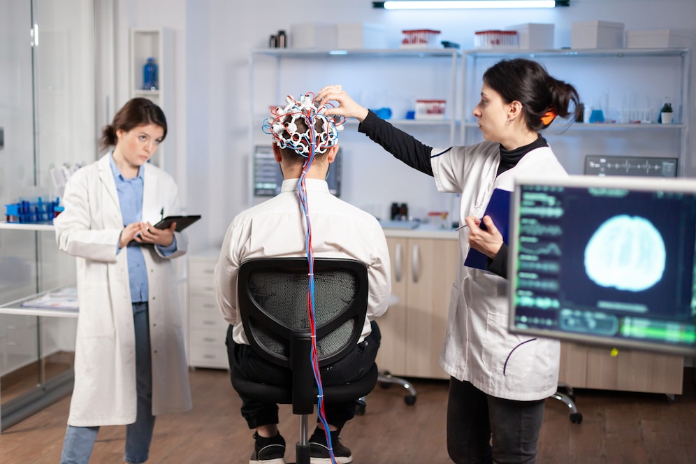 Two female scientists conduct a brain scan on a male patient