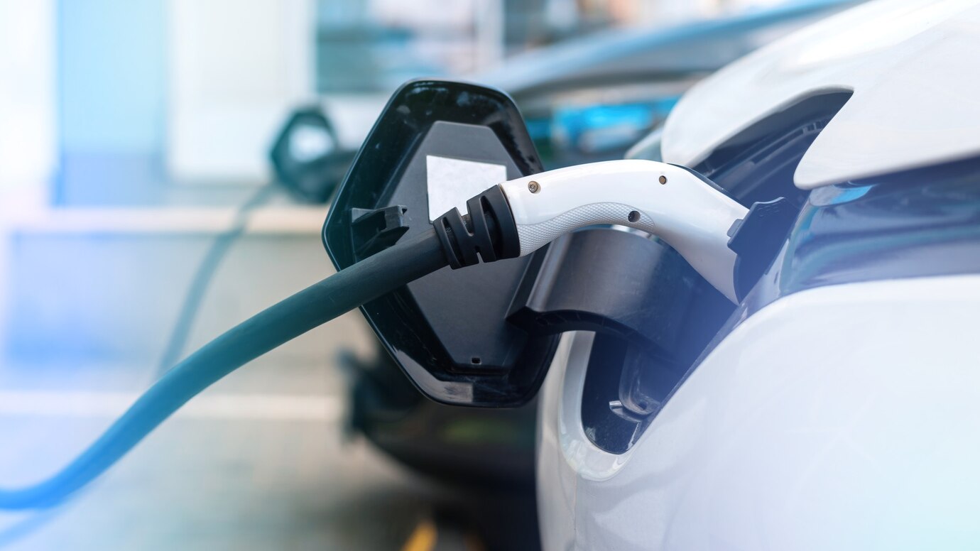 Electric vehicle charging at a station with a cable connected to its port.