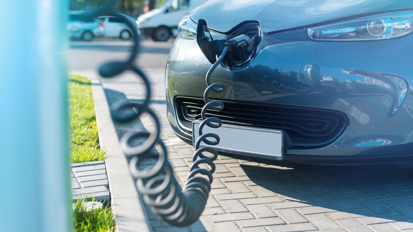 Electric car charging at a street station with a spiraled cable